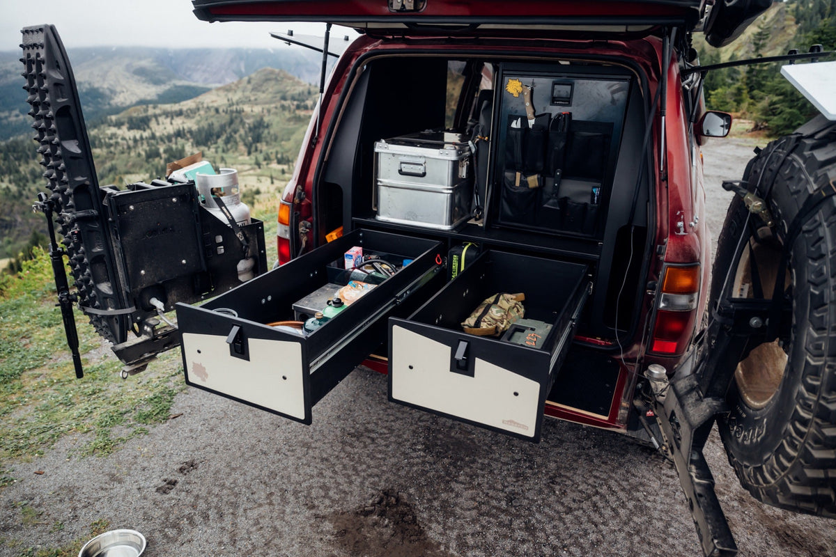 Rear of the red Land Cruiser with both Wasatch Overland drawers pulled out, a mountain valley behind