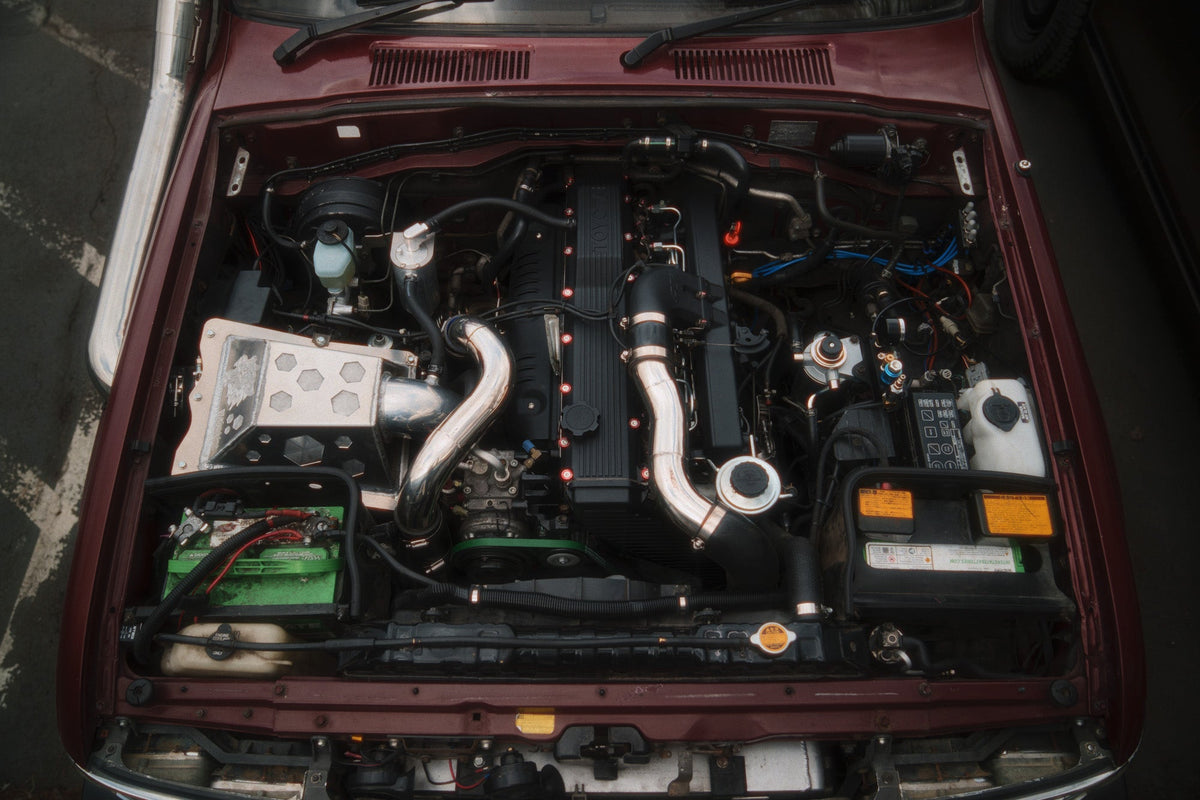 Overhead view of the HDJ81 engine bay, the 1HD-T turbo diesel with polished intake piping, under the open red hood