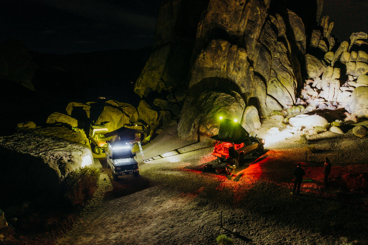 Camp at night in the Alabama Hills, trucks lit up among the boulders