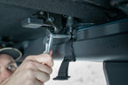 Fitting a mounting strap to the Bronco's roof hardware with a wrench