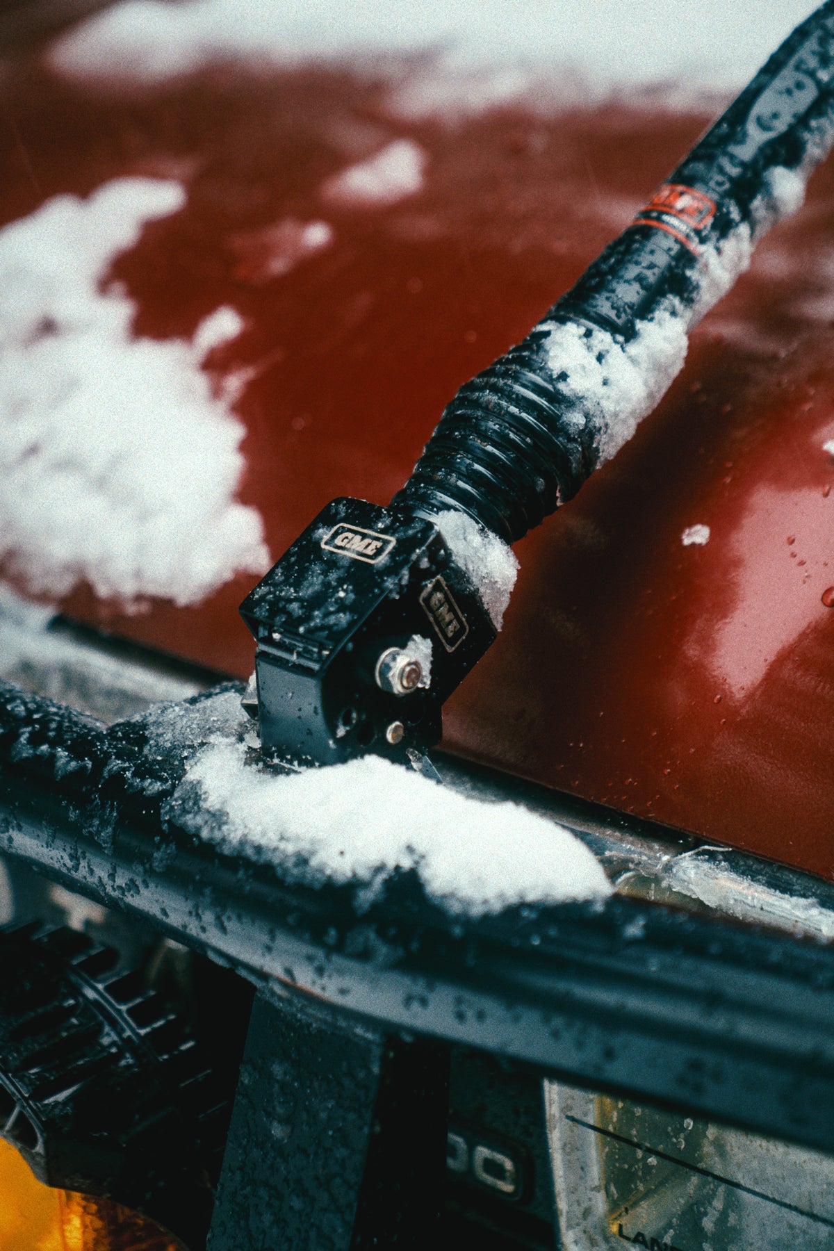 The fold-down bracket on the bull bar dusted with snow, antenna laid back