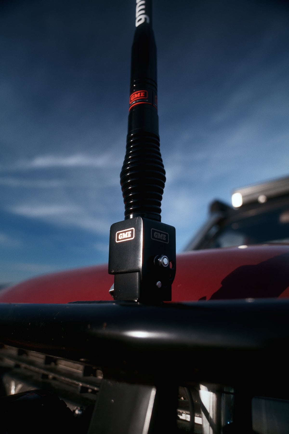 The fold-down bracket and GME antenna on the bull bar against a deep blue sky