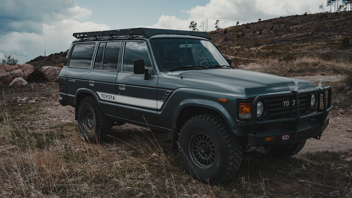 Gray 60 Series Land Cruiser with a Mineral rack and steel bumper on a dirt hilltop