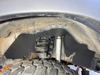 Ark rubber splash guard fitted in a Land Cruiser HDJ80 front wheel well, behind the coil spring and shock
