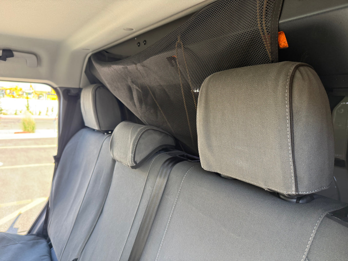 Escape Gear canvas seat covers, Ineos Grenadier, Grey rear headrests and seat backs below a cargo net