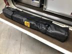 Eezi-Awn K9 Fold A Chair packed in its black carry bag on a vehicle's rear load floor