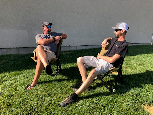 Eezi-Awn K9 Fold A Chair, two people seated in Beige chairs on a lawn