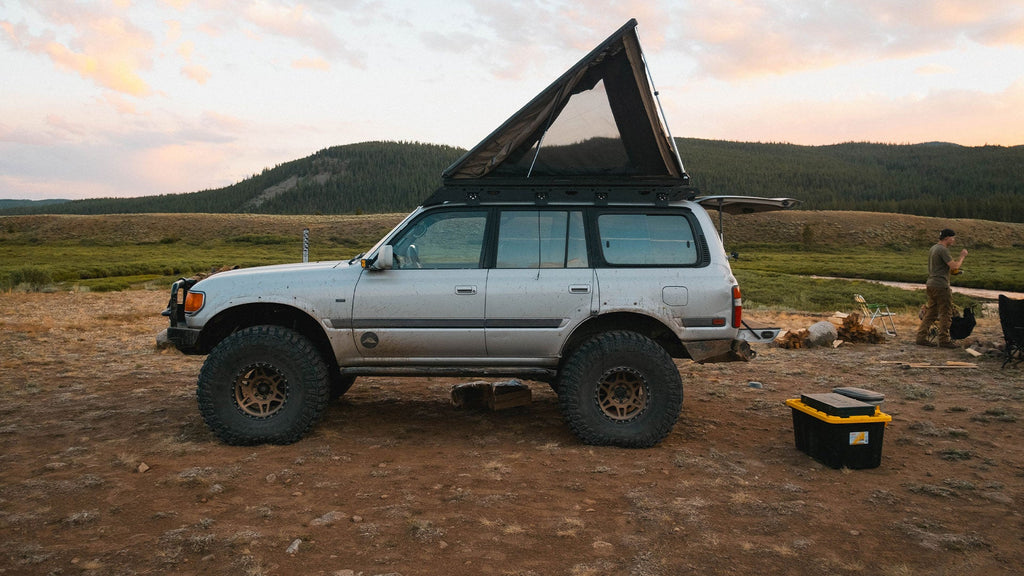 Silver 80 Series Land Cruiser with a rooftop tent on a Sherpa La Sal rack at a meadow camp