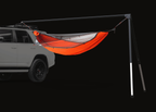 The Outpost hammock stand fixed to the roof rack of a white SUV, legs down at the far end, an orange hammock hung beneath
