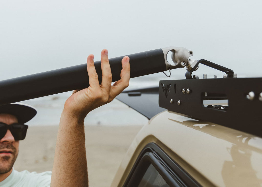 Setting the Outpost crossbar into its rack mount on a tan truck