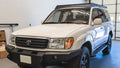 Sherpa Oxford roof rack on a white 100 Series Land Cruiser in a shop, front three-quarter