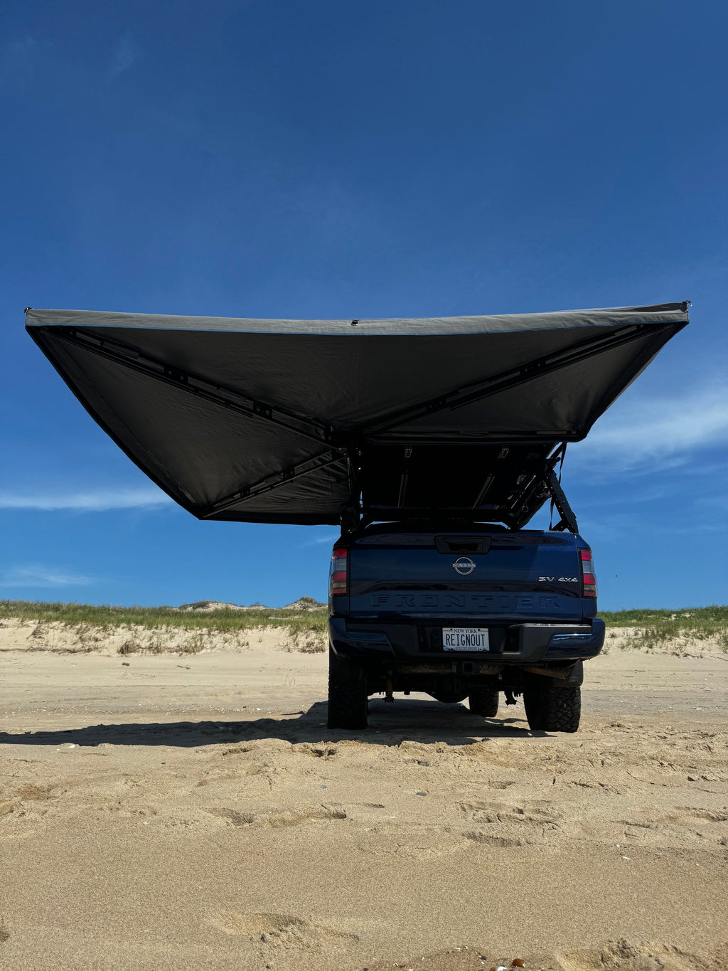 The Reign 270 open behind a pickup, showing the 270-degree shape that wraps from the side around the back of the vehicle