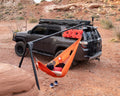 The Outpost stand mounted to a black 4Runner in red desert, an orange hammock slung from it