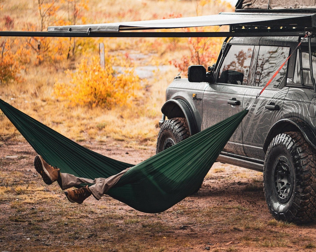 A green hammock slung from the Outpost on a grey Bronco in autumn scrub