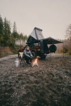 The Reign 270 open in daylight with its support legs down, covering a camp chair, table and stove