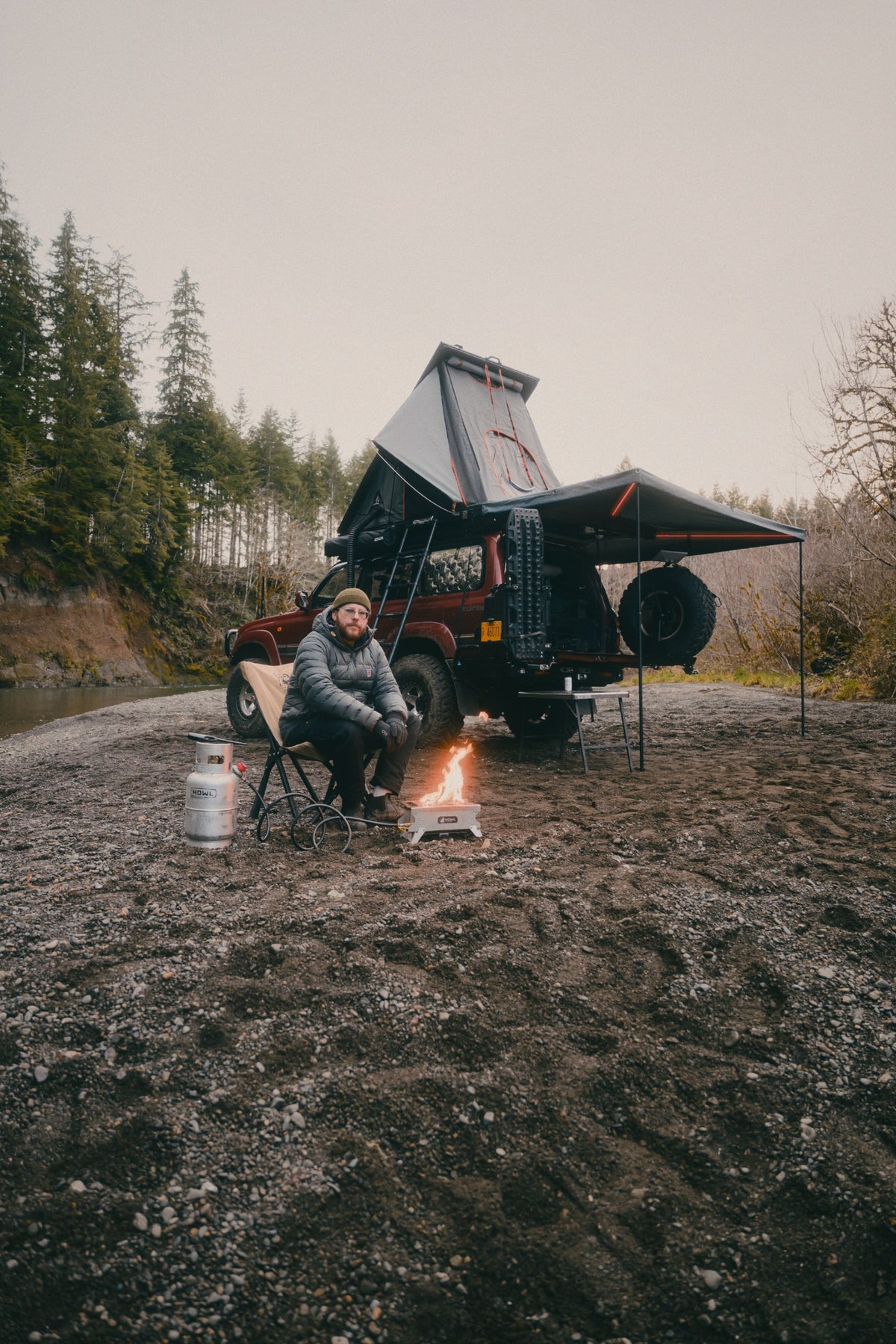 The Reign 270 open in daylight with its support legs down, covering a camp chair, table and stove