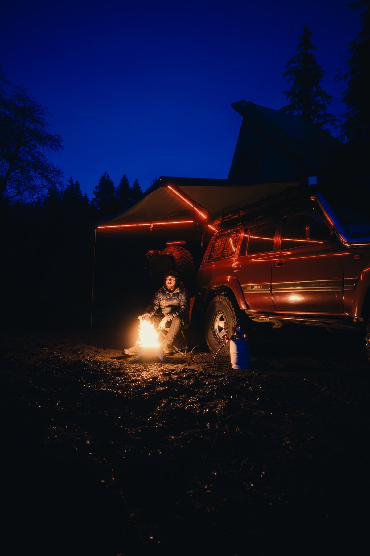 The Reign 270 deployed at dusk with its arm LEDs lit red, wrapping from the side of an 80 Series Land Cruiser around toward the rear