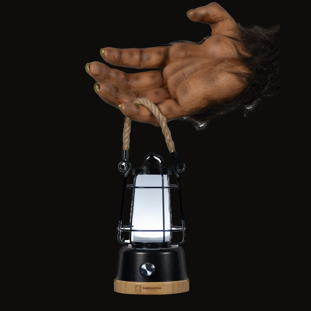 A prosthetic Sasquatch hand holding the rope lantern by its rope handle