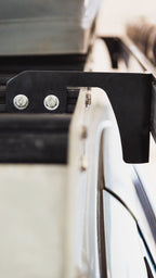 Sherpa awning mount bolted to a crossbar end, two bolts through the tab