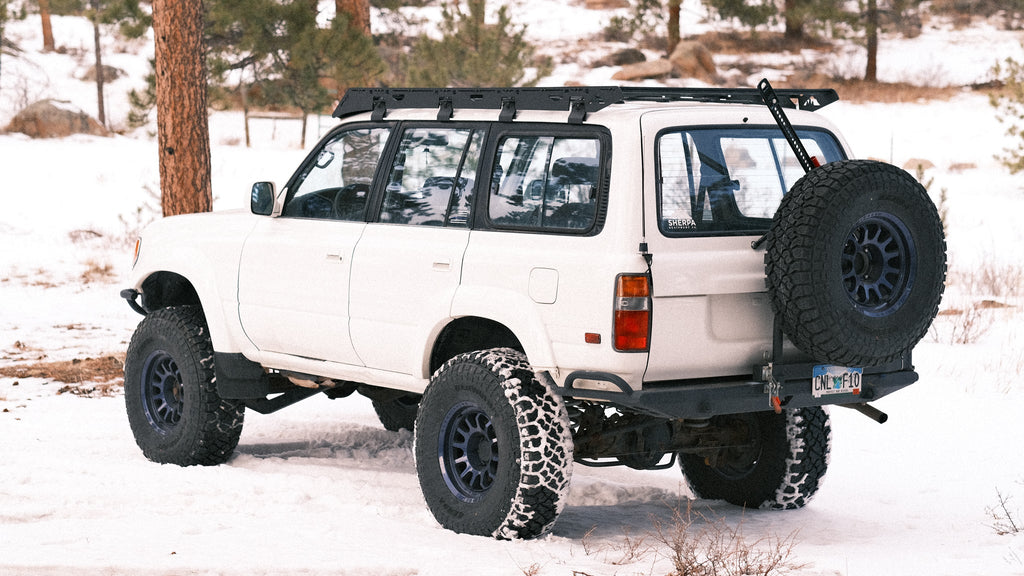 White 80 Series Land Cruiser on large tires in snow, La Sal rack and rear tire carrier