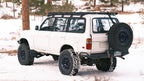 White 80 Series Land Cruiser on large tires in snow, La Sal rack and rear tire carrier