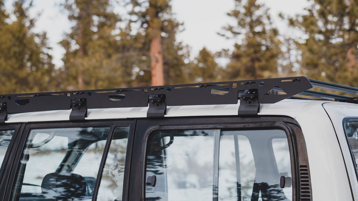 La Sal sideplate running the length of a white 80 Series roof, gutter mounts at each crossbar